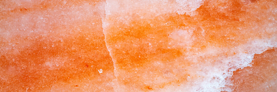 Salt rock formation shows natural mineral patterns with shades of pink and orange in a natural setting