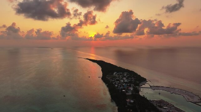 Aerial view of the lush tropical island of Fulhadhoo during a vibrant sunset with golden clouds and calm turquoise waters Fulhadhoo, Baa Atoll, Maldives.