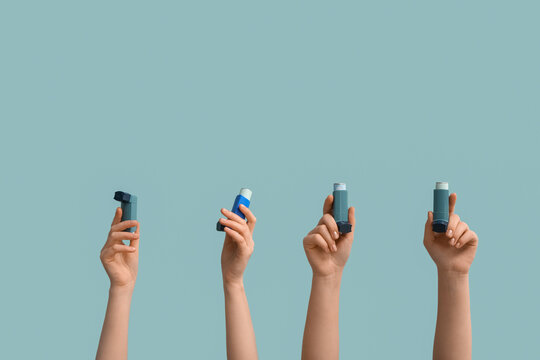 Female hands with modern asthma inhalers on blue background