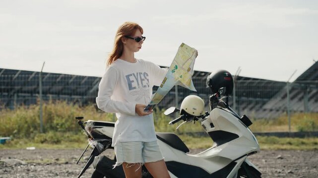 Young woman traveler holding map near scooter