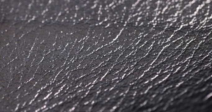The leather material from the bag reflects soft light, a dark textured material with uneven protrusions and deep creases on the leather surface with an authentic look and clear details.