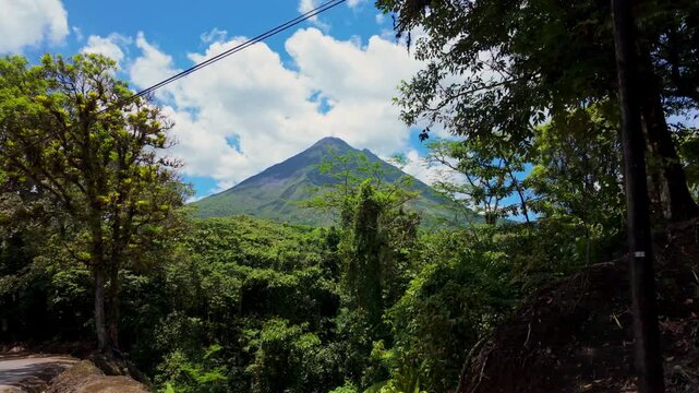 Arenal volcano revealing behind a tropical rainforest in costa rica