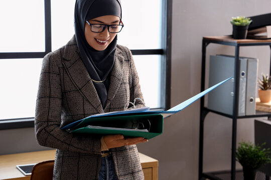 Young Muslim businesswoman with document folders in office