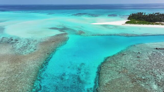 Aerial view of the crystal clear turquoise lagoon, vibrant coral reefs, and white sand beaches of a tropical island in Fulhadhoo, Baa Atoll, Maldives.