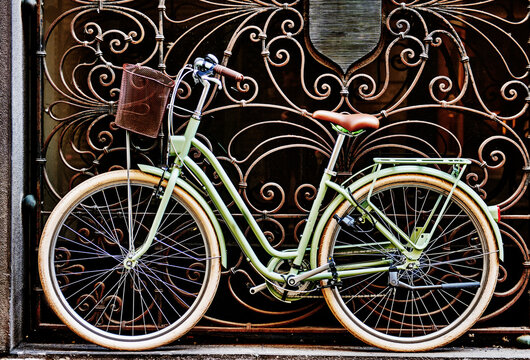 Old fashioned green bicycle leaning against a decorative metal gate, Turin, Northern Italy, Europe 