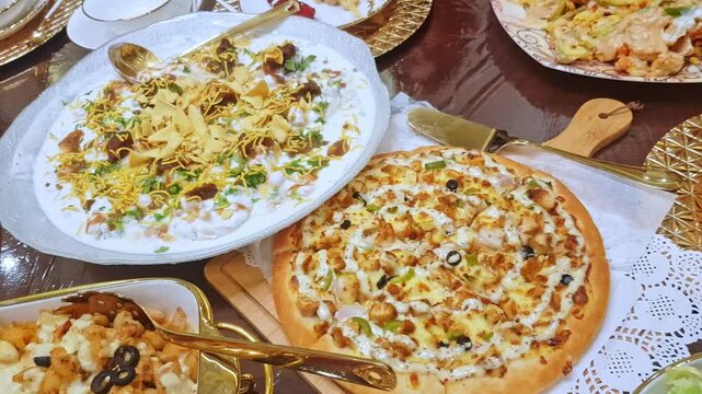 Variety of multiple food dishes, pizza, pasta and vegetable salad includes lettuce, olive and cucumber served in dinner on dining table.