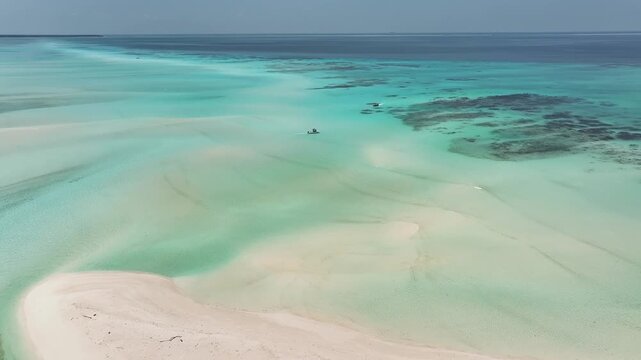 Aerial view of a pristine white sandbar surrounded by turquoise lagoon waters and coral reefs in Fulhadhoo, Baa Atoll, Maldives.