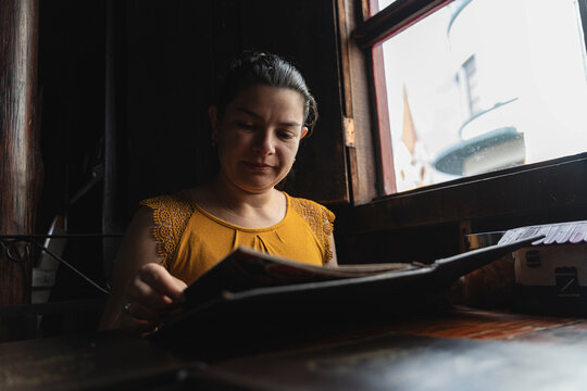 Woman selecting food from menu in dark restaurant