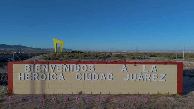 A high-angle perspective of the "Umbral del Milenio" (Millennium Threshold) monument, a massive yellow geometric structure at the entrance of Ciudad Juarez, Chihuahua. Mexico.