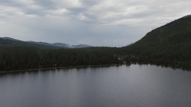 Drone footage of calm Multinsky Lakes surrounded by dense taiga forest and mountain ridges under dramatic overcast clouds, Ust-Koksinsky District, Altai Republic, Russia