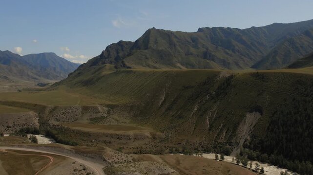 Wide aerial landscape of the Chuya and Katun rivers meeting in a mountain valley, with dry steppe hills and clear sky in Altai Republic, Russia