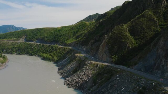 Aerial landscape footage of the Chuysky Trakt mountain road curving along the Katun River, Altai Republic, Russia, with cars driving beside rocky cliffs