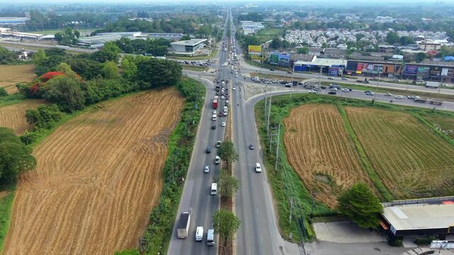 High-quality 4K aerial view of a regional highway and city expansion, highlighting traffic logistics and the intersection of rural and urban landscapes.