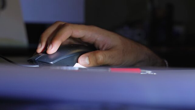 Close-up of a person's hand writing in a lined notebook with a red pen. The scene is dimly lit, suggesting a late-night study session or creative journaling in a home office.