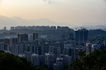 Fototapeta premium Distant sunset scenery in Fuzhou. The sun slowly sets behind Tianshan Mountain, overlooking the Minjiang River. Riverside city buildings line the bank, blending mountain, river and urban architecture.