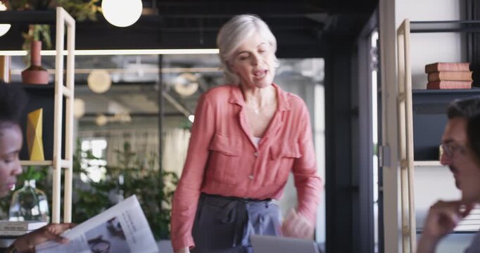 Laptop, business people meeting and mature woman consulting on online design, research or development process. Group leader, creative agency and manager feedback, teamwork or explain webdesign plan