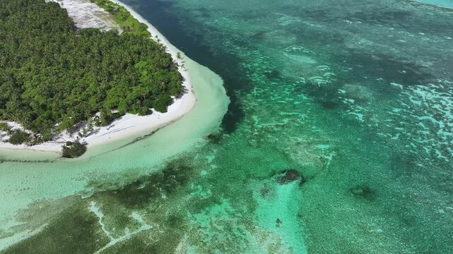 Aerial view of the lush tropical vegetation and white sandy beaches surrounded by crystal clear turquoise waters and coral reefs in Goidhoo, Baa Atoll, Maldives.
