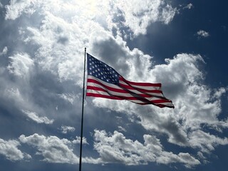 Obraz premium us flag waving on flag pole with dramatic storm clouds in the background