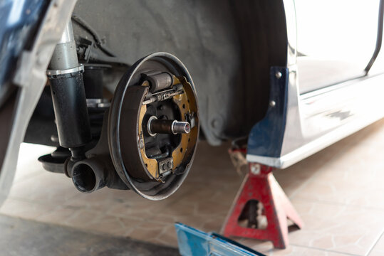 Close up of car brake drum system during repair with wheel removed showing suspension and brake components vehicle maintenance service concept