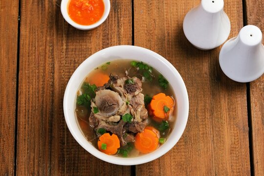 Top view of oxtail soup or sop Buntut with vegetables in clean composition, highlighting traditional Indonesian dish and minimal food styling.
