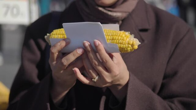 Enjoying corn on the street in a busy market