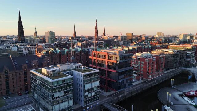 Aerial view of the historic Speicherstadt warehouses, church spires, and modern architecture during sunset in Hamburg, Hamburg, Germany.