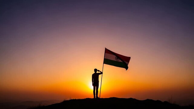 Silhouette of a lone person standing on a hilltop saluting the Indian flag at dawn