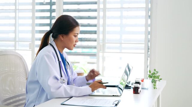 Doctor looking at laptop screen writing in notebook for research planning or medical tech innovation in hospital office. Healthcare medic worker, research.