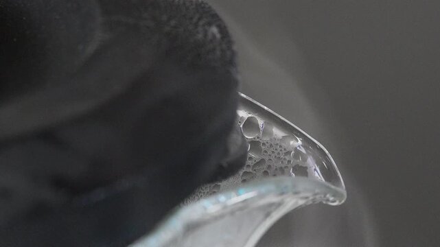 4K macro video of white steam and water vapor rising from the spout of a glass kettle, Condensation and heat of boiling water representing morning routines tea preparation.