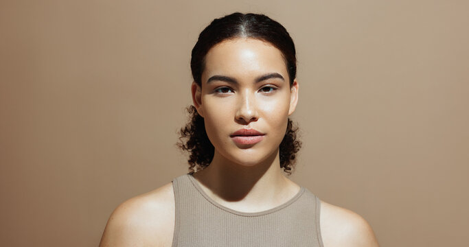 Portrait, skincare and woman in studio, glow and natural dermatology on brown background space. Confidence, healthy skin and serious person with beauty cosmetics for shine, wellness and cosmetology