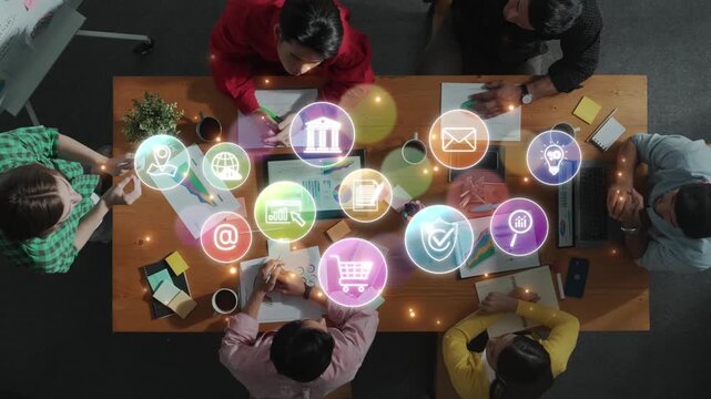 A diverse group of professionals collaborate around a table, utilizing digital icons to represent various business concepts and communication strategies in a modern office setting. Raster