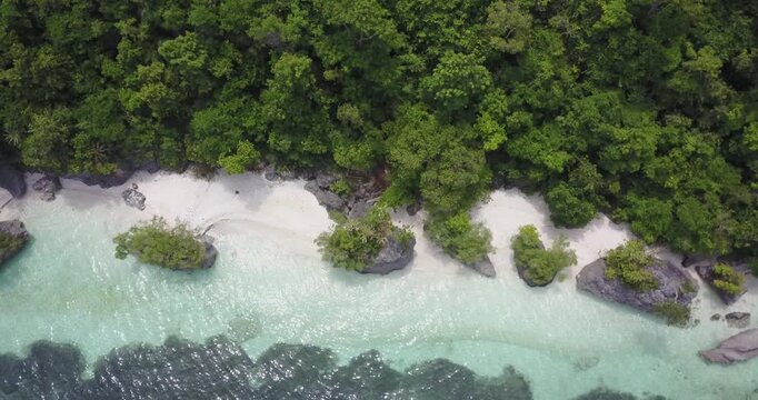 Drone shot ascending from low altitude to top down aerial view over Secret Beach with turquoise water, rocks and dense jungle coastline in Siquijor, Philippines