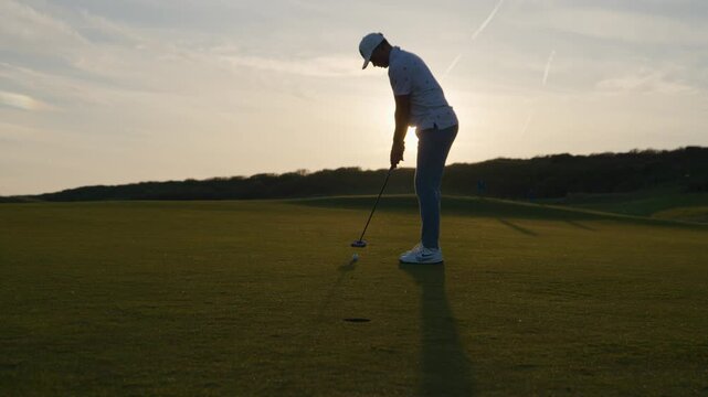 Golfer Putts Golf Ball in Hole on Green - Golden Hour Slow Motion