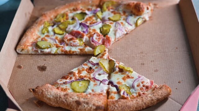 A hand is reaching for a slice of pizza from a takeout box, leaving behind only crust and a few toppings. Timelapse of eating Italian pizza