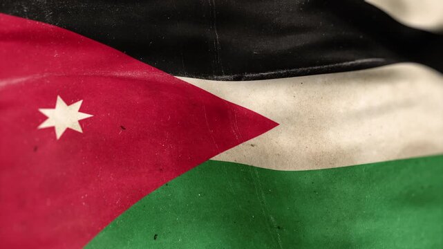 A Jordan flag, made of old cloth, dirty and stained, flutters in the wind. A Worn Jordan Flag Waves In The Breeze.