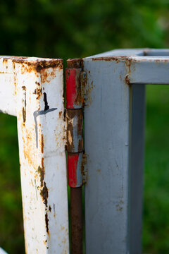 a rusty metal hinge on a crossbar that is starting to corrode
