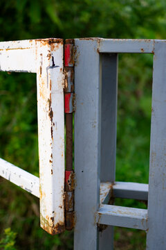 a rusty metal hinge on a crossbar that is starting to corrode