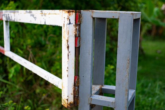 a rusty metal hinge on a crossbar that is starting to corrode