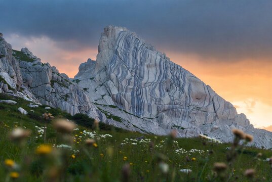 Towering gneiss rock formation intricate foliation patterns alpine meadow foreground at dawn landscape photography