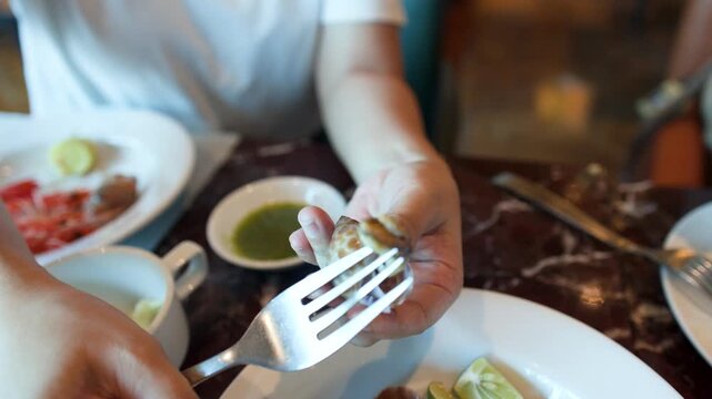 Asian Woman Using Fork to Extract Snail Meat at International Buffet