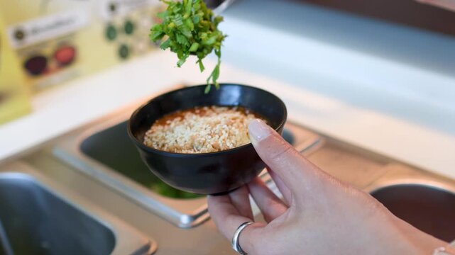Person Adding Fresh Cilantro to Dipping Sauce at a Buffet Station