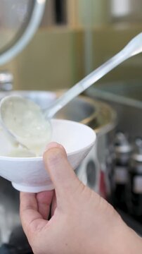 Person Serving Hot Rice Porridge with Ladle at Breakfast Buffet