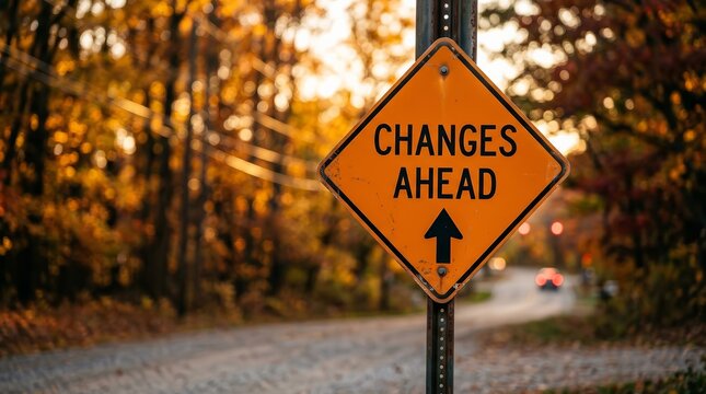 Changes ahead sign on a street with autumn trees and a blurred background.