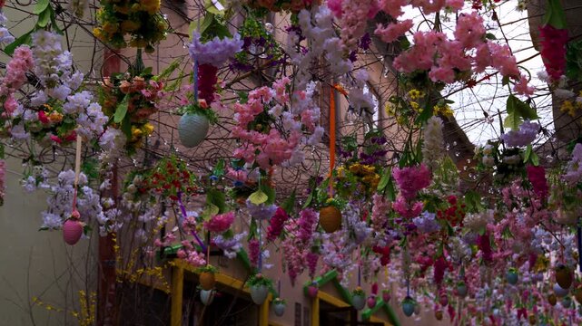 Colorful Easter flowers and hanging eggs spanning narrow alley, looking up through decoration, Czech Republic