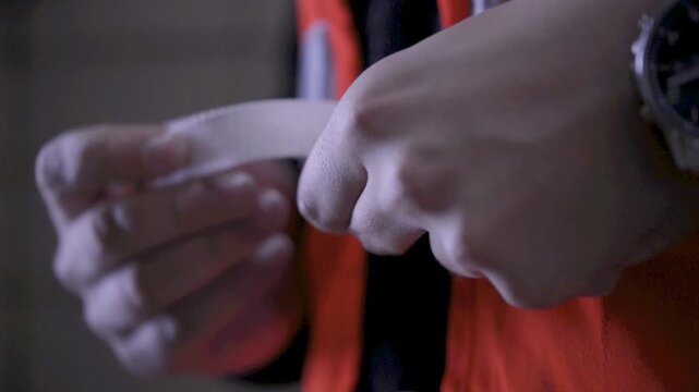 Worker adjusts and fastens safety vest straps in close-up, indoor setting