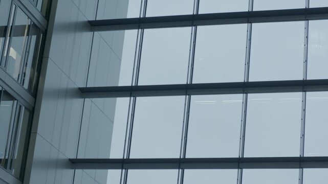 Large modern glass windows with metal beams in a quiet indoor architectural setting