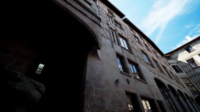 Historical stone and wood facades in a narrow alley in the center of Limoges with an upward camera movement.