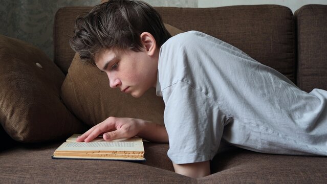 Young man caucasian teenager read book study at home education concept. A young man, a teenager reading a book