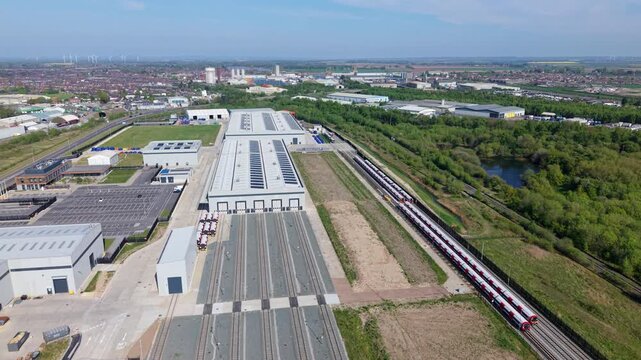 Aerial view of a modern train manufacturing facility and rail depot with solar panels on rooftops and trains on tracks in Goole, England, United Kingdom.