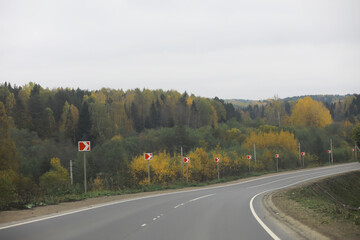 Fototapeta premium Winding Road through Autumn Forest with Directional Signs on Overcast Day